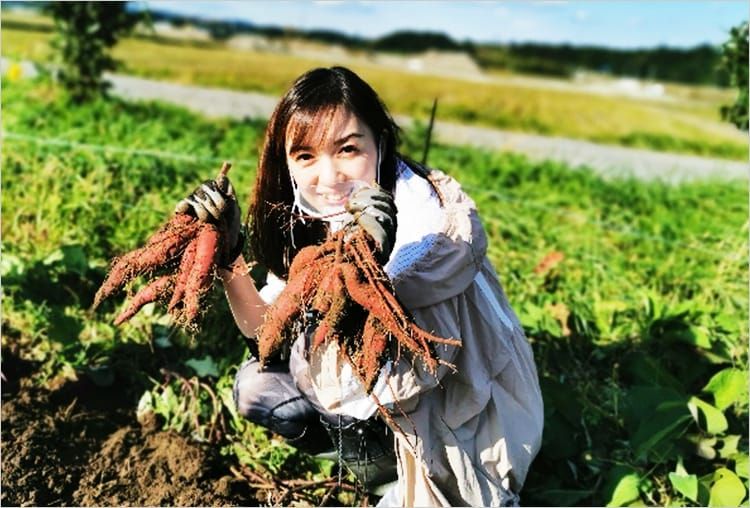 高橋麻里江さんが両手にサツマイモを持ち笑顔を浮かべている写真